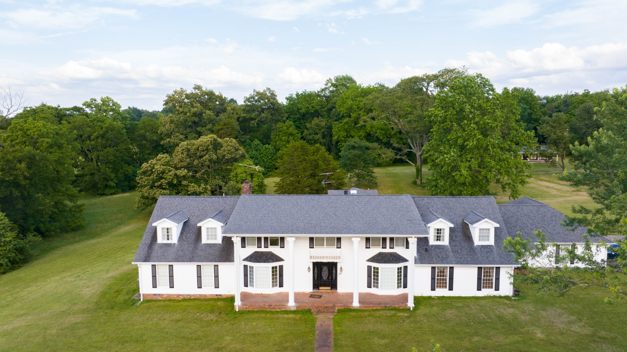 an aerial view of residential houses with outdoor space and trees