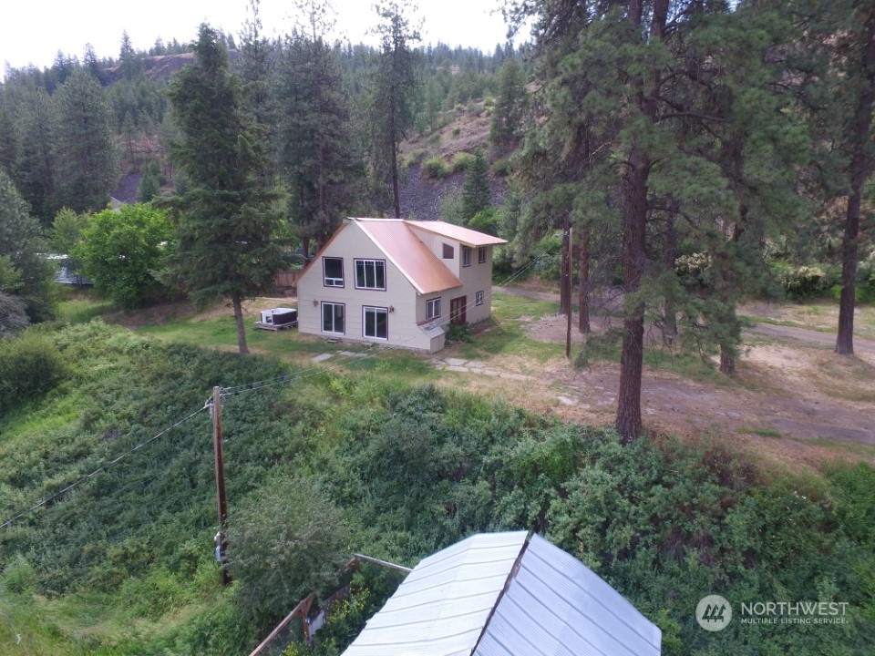 a view of a house with a yard and large trees