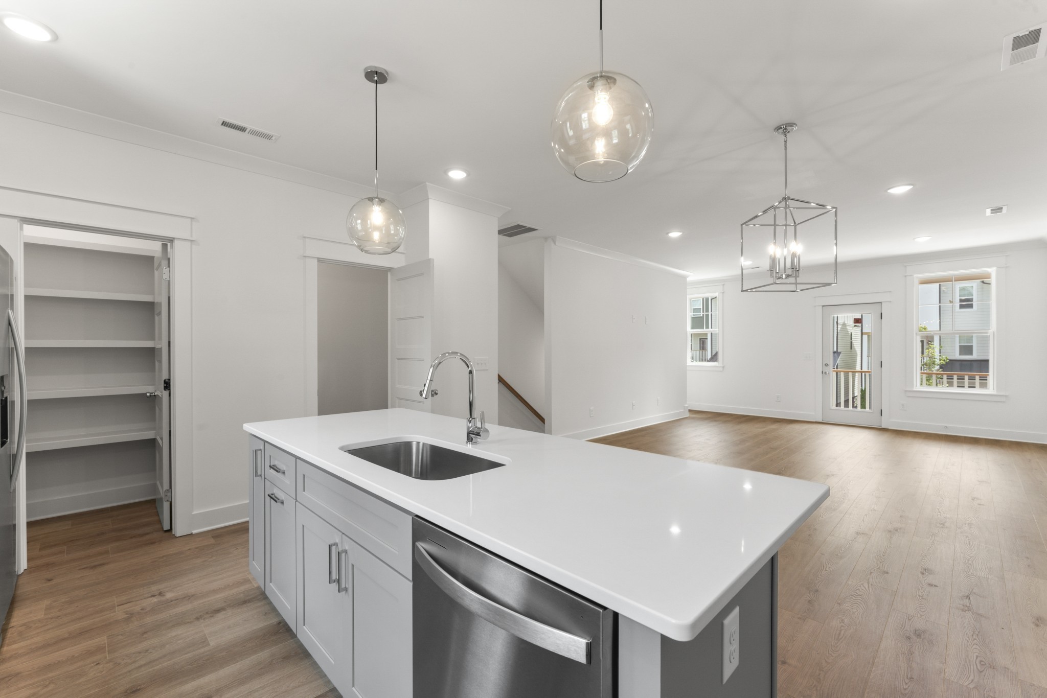 a kitchen with a sink chandelier and wooden floor