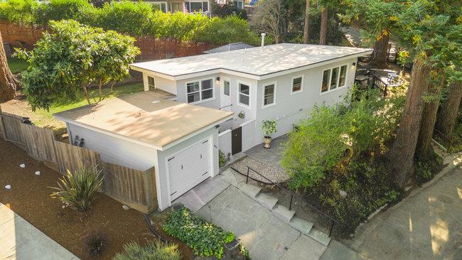 a aerial view of residential houses with yard and trees in the background