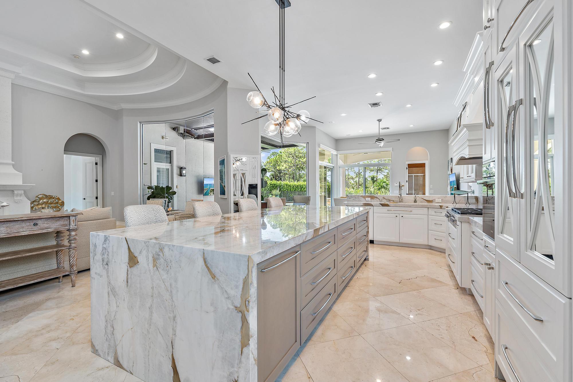 a large white kitchen with a large window and stainless steel appliances