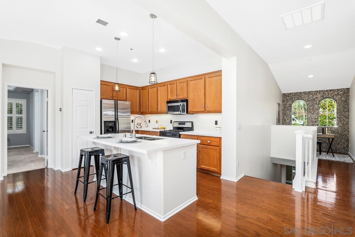 a kitchen with stainless steel appliances granite countertop a refrigerator a stove top oven a sink dishwasher and white cabinets with wooden floor