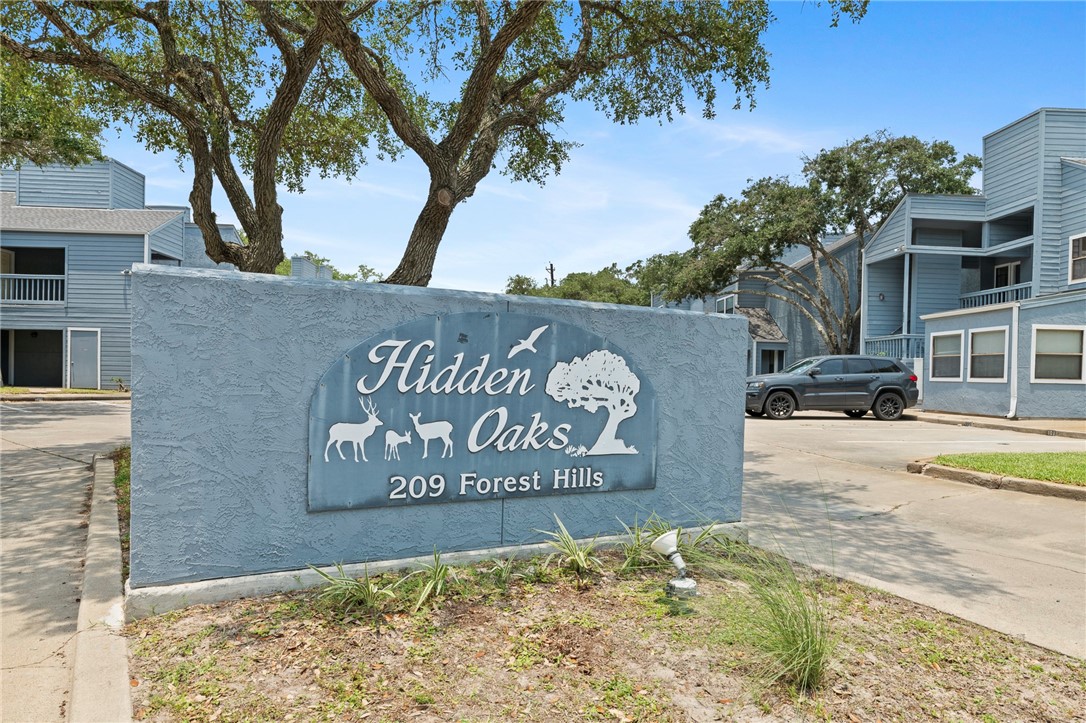 a view of an entrance to house with yard and sign board