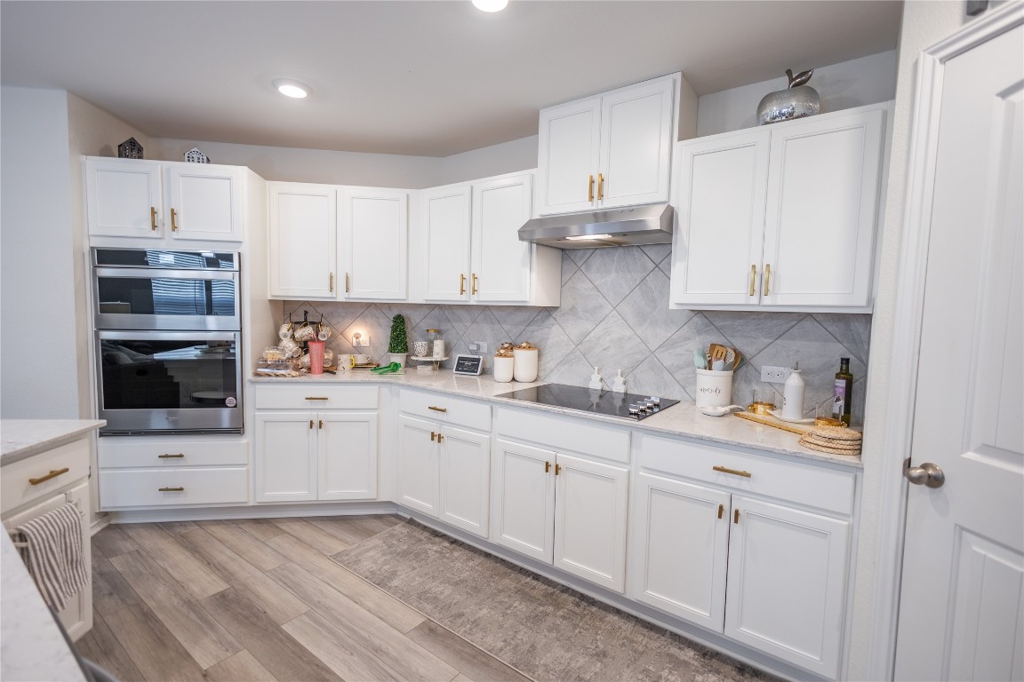 a kitchen with granite countertop white cabinets and stainless steel appliances