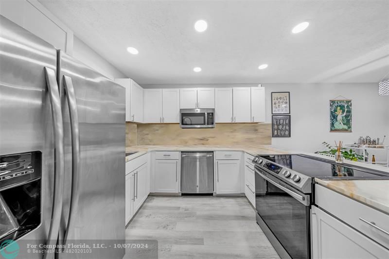 a kitchen with stainless steel appliances granite countertop a stove a sink and a refrigerator