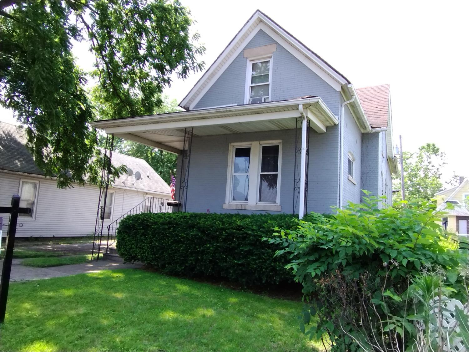 a view of a house with a yard plants and large tree