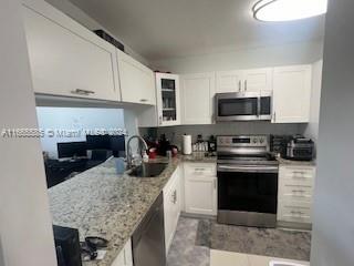 a kitchen with stainless steel appliances granite countertop a stove top oven a sink dishwasher and a microwave oven with white cabinets