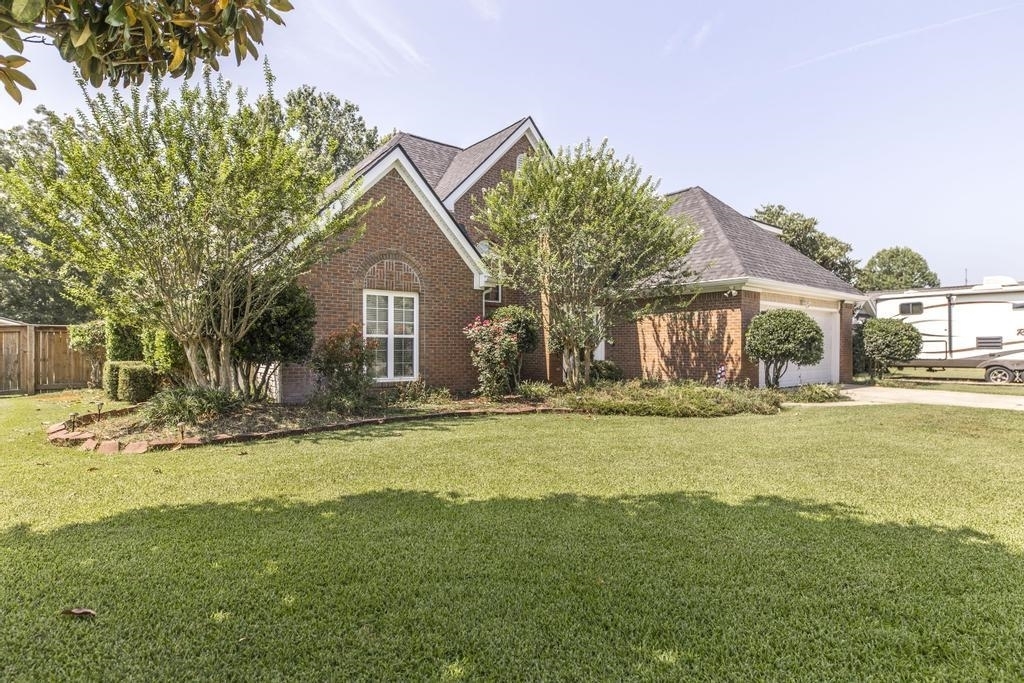 a front view of a house with a garden and trees