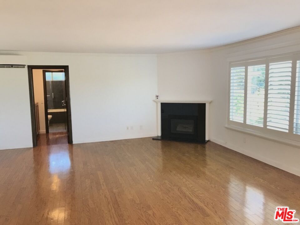 a view of an empty room with a window and a fireplace