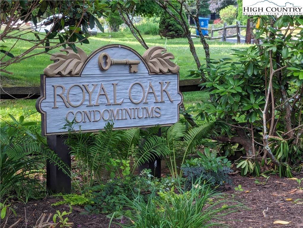 a view of sign board with plants and trees