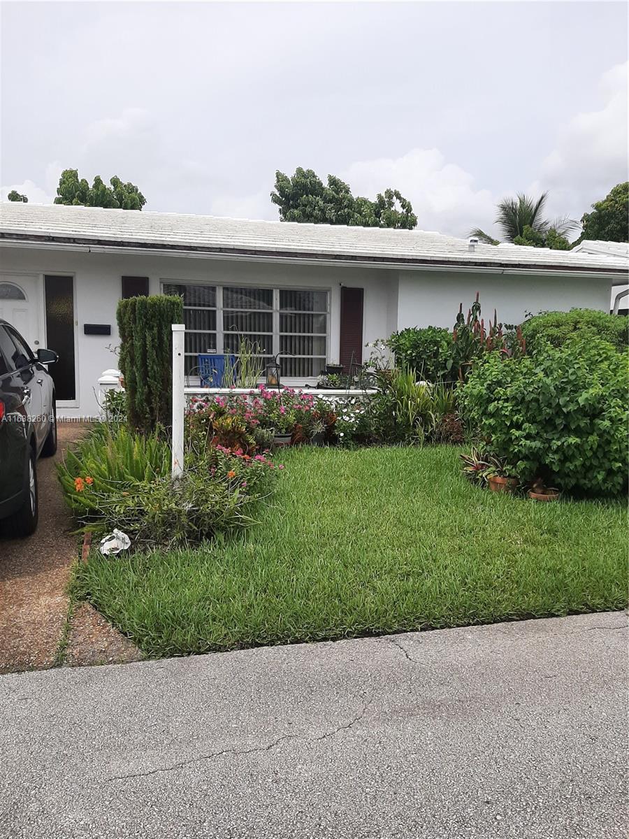 a front view of a house with a yard and potted plants