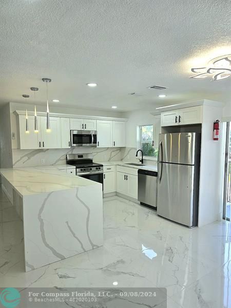 a kitchen with stainless steel appliances granite countertop a refrigerator sink and stove