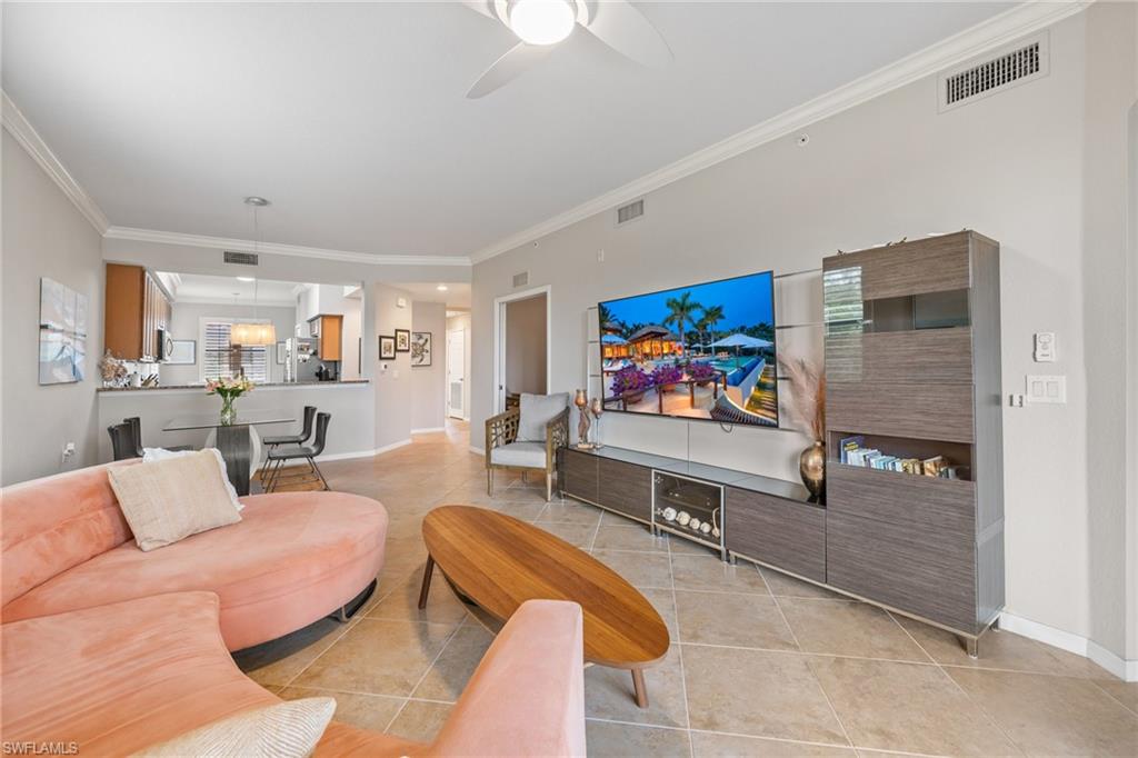 Tiled living room featuring ceiling fan and crown molding