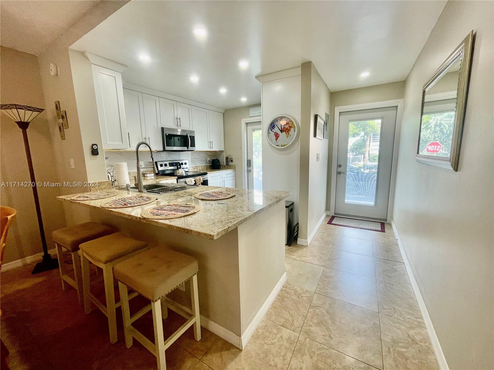 a kitchen with kitchen island granite countertop wooden cabinets and refrigerator