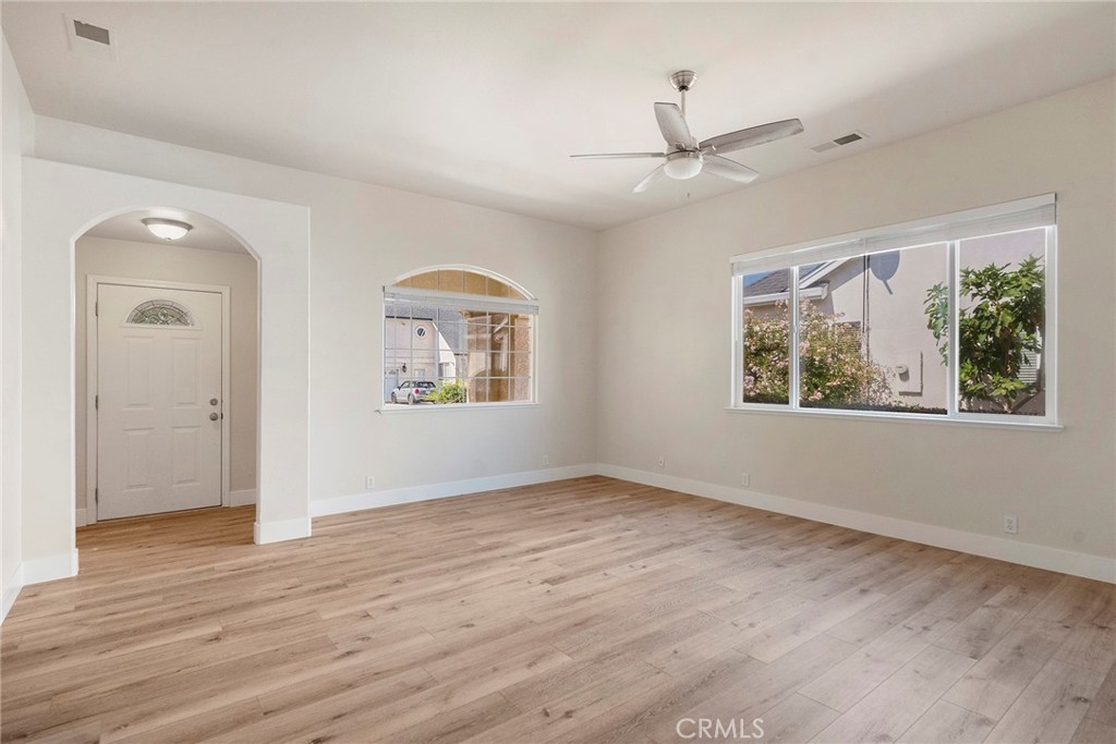 an empty room with wooden floor ceiling fan and windows