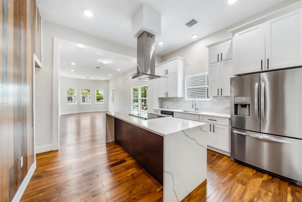 a kitchen with stainless steel appliances a refrigerator a sink dishwasher a stove and white cabinets with wooden floor