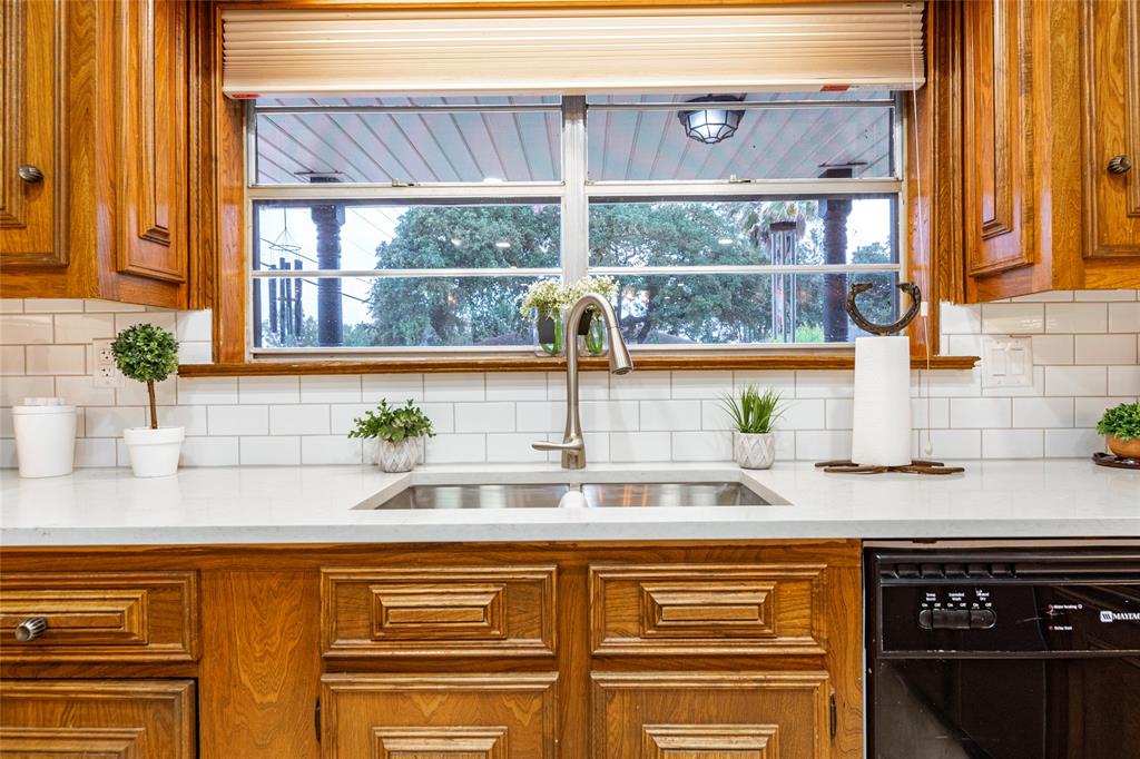 This is a spacious kitchen featuring traditional wooden cabinetry, white appliances, including a side-by-side refrigerator and a gas range, and tiled flooring. Natural light enters through a window above the sink.