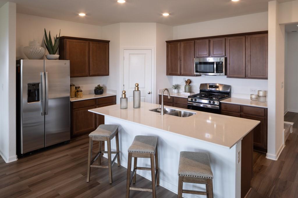 a kitchen with kitchen island a refrigerator stove microwave and cabinets