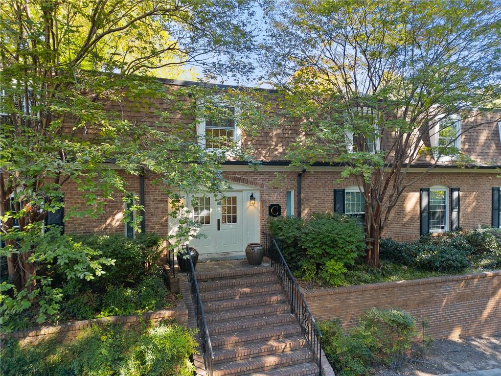 a front view of a house with trees and plants