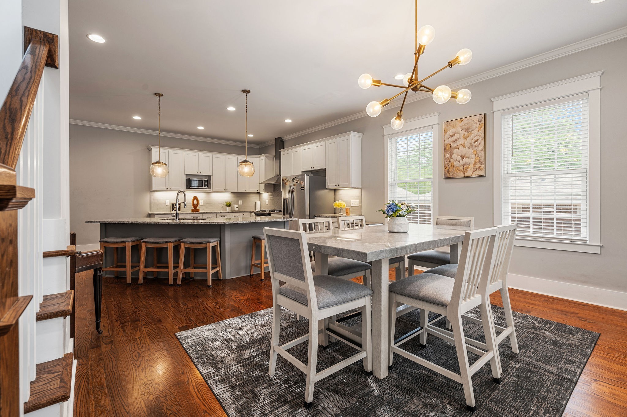 a dining room with stainless steel appliances kitchen island granite countertop a table chairs and a refrigerator