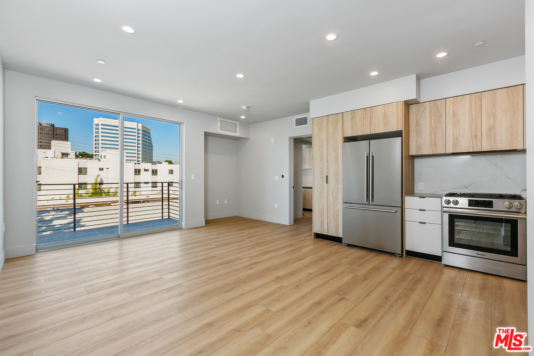 a view of kitchen with stainless steel appliances wooden floor and window