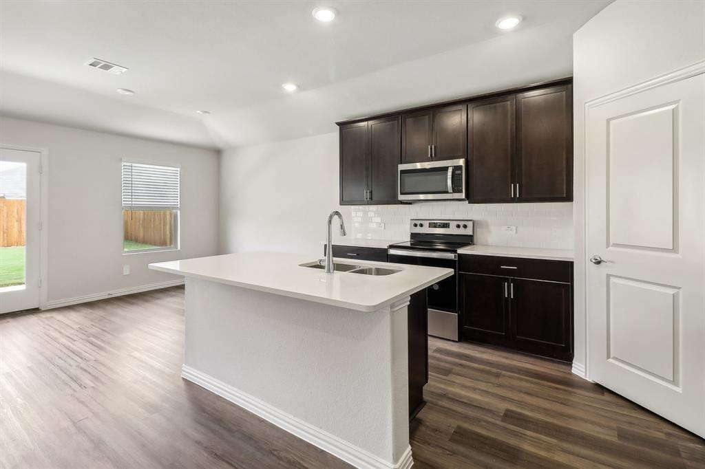 a kitchen with stainless steel appliances kitchen island granite countertop a stove and a refrigerator