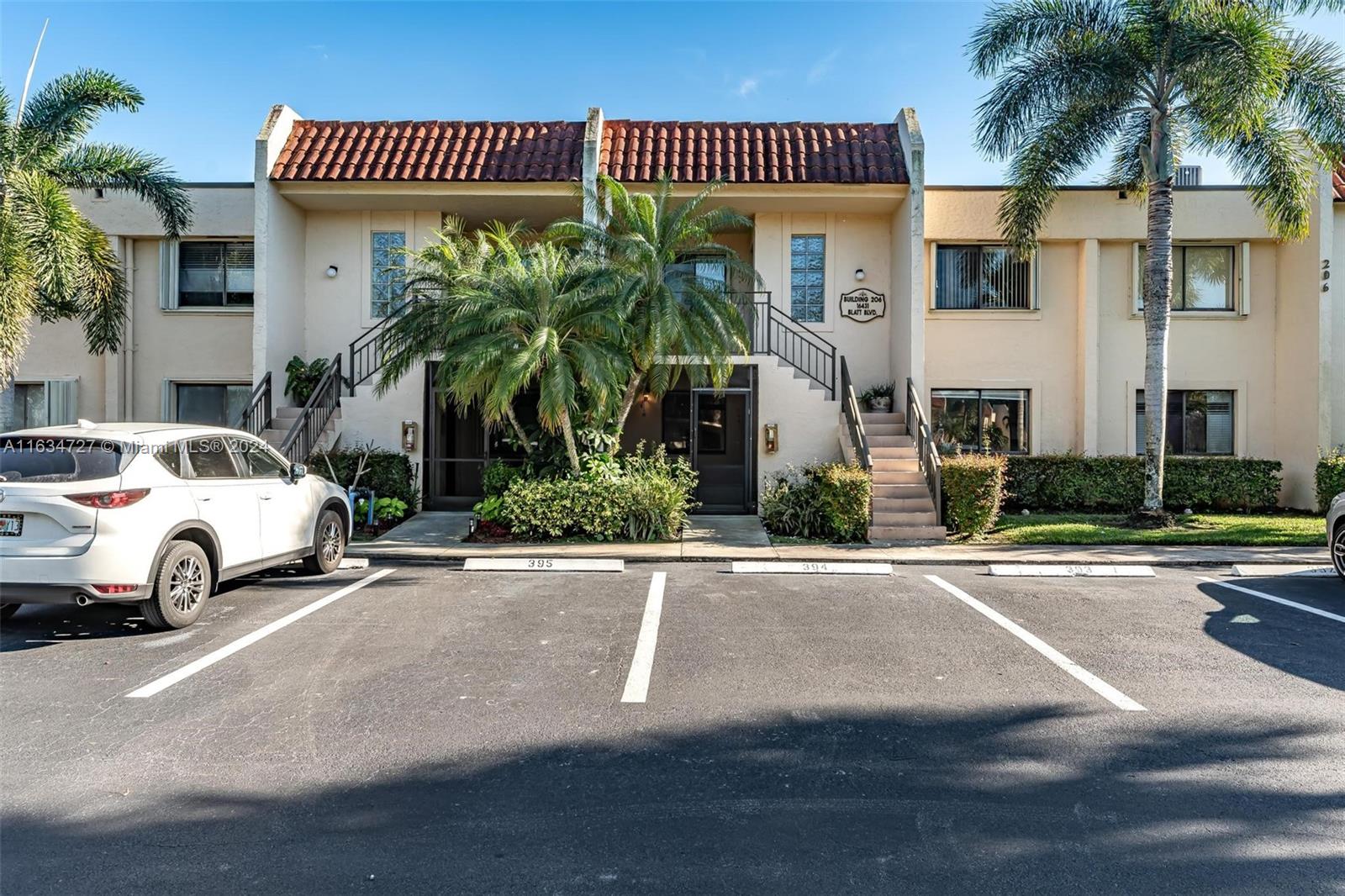 a view of a white apartments with palm trees