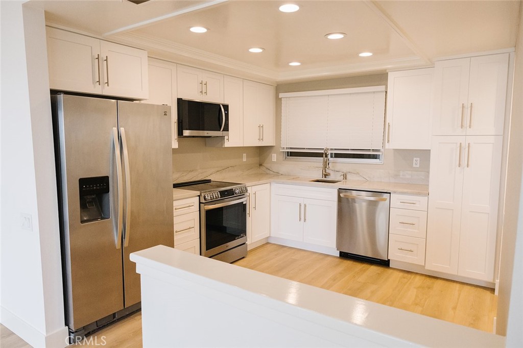 a kitchen with a sink white cabinets and stainless steel appliances