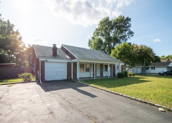 Ranch-style home featuring a front lawn, a garage, and a porch