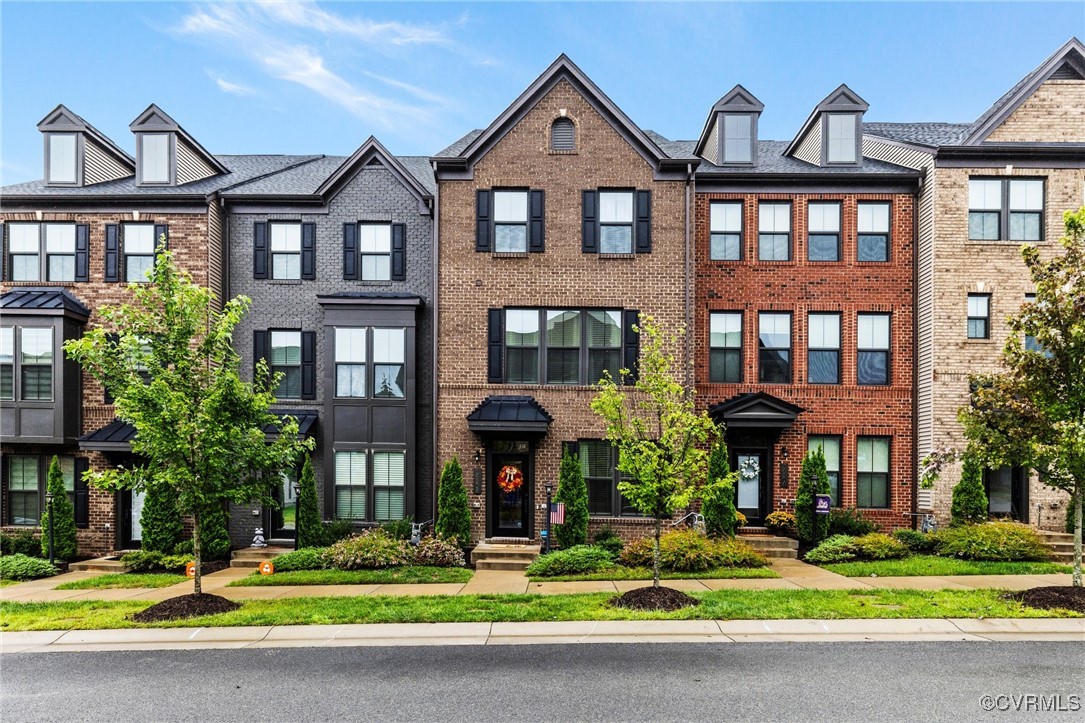 a front view of a residential apartment building with a yard and potted plants