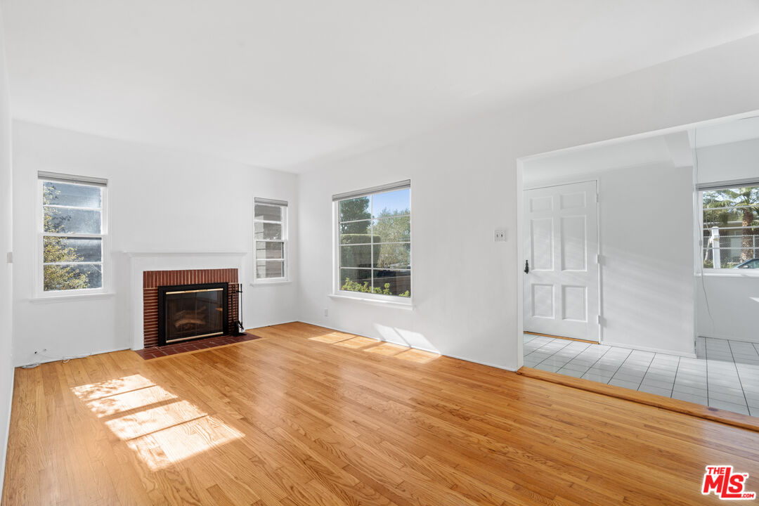 a view of empty room with fireplace and wooden floor