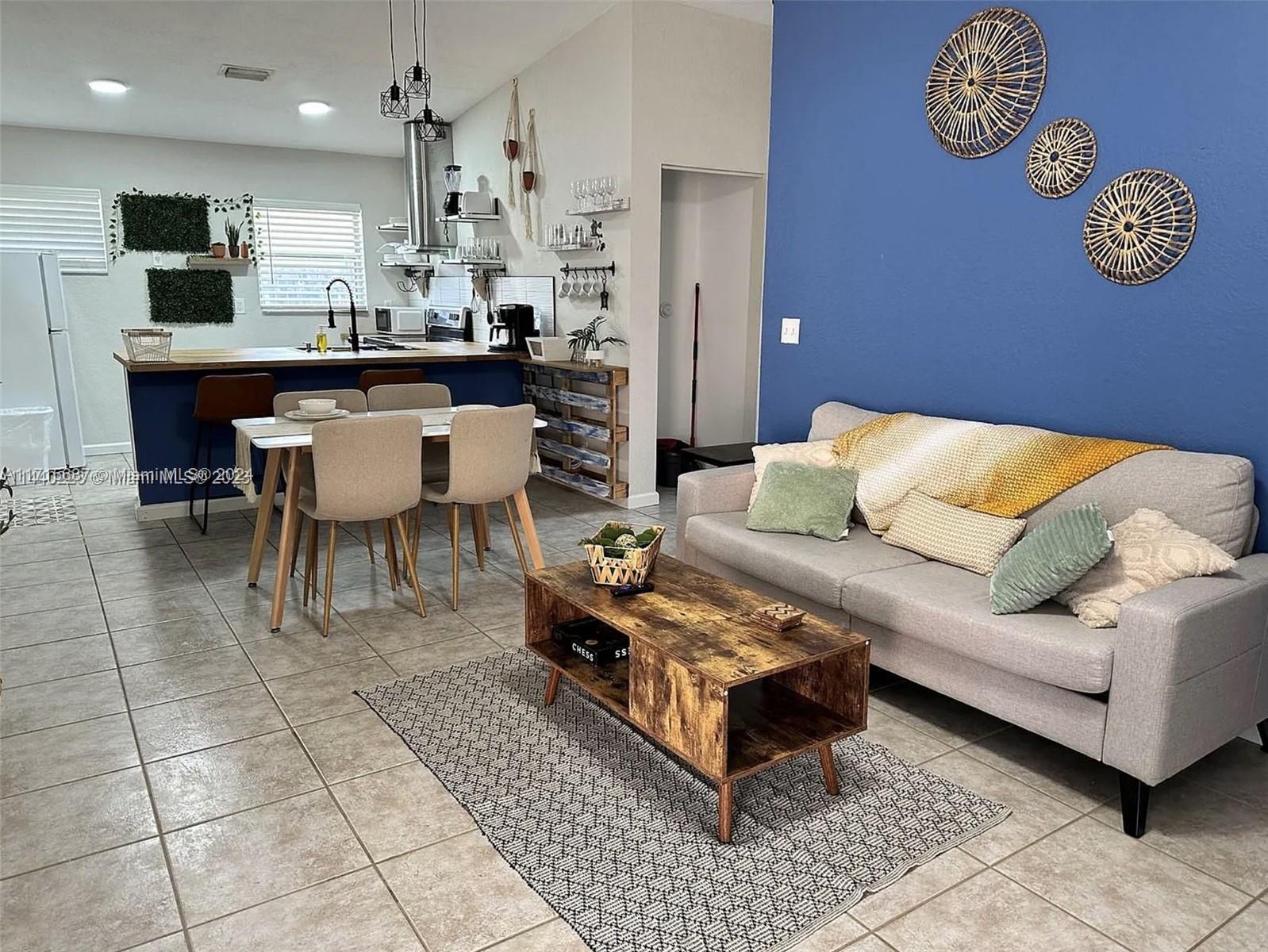 a living room with a couch and a dining table with wooden floor