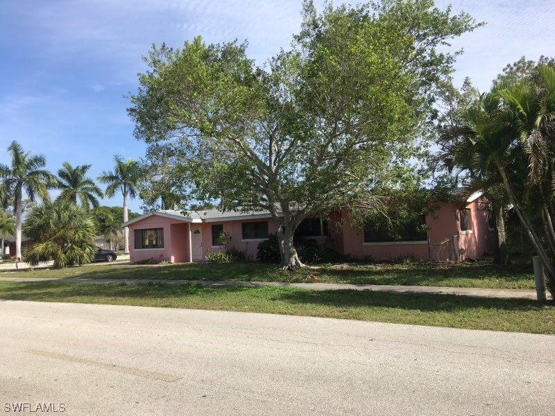 a view of a house with a yard and large trees