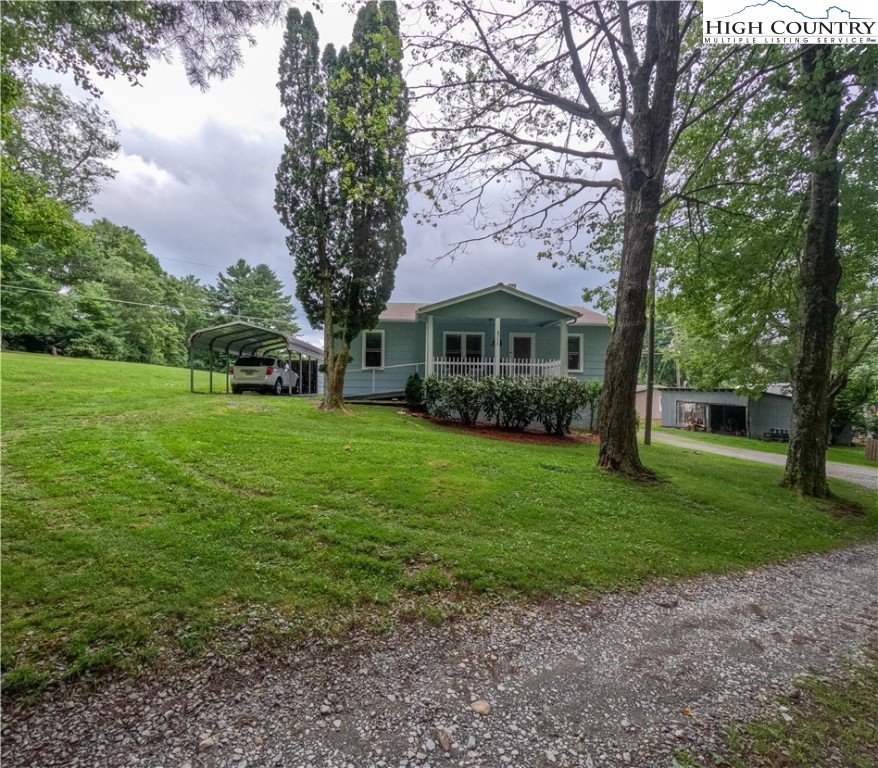 a view of house in front of a big yard with large trees