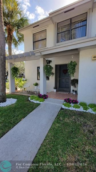 a front view of a house with a yard and potted plants