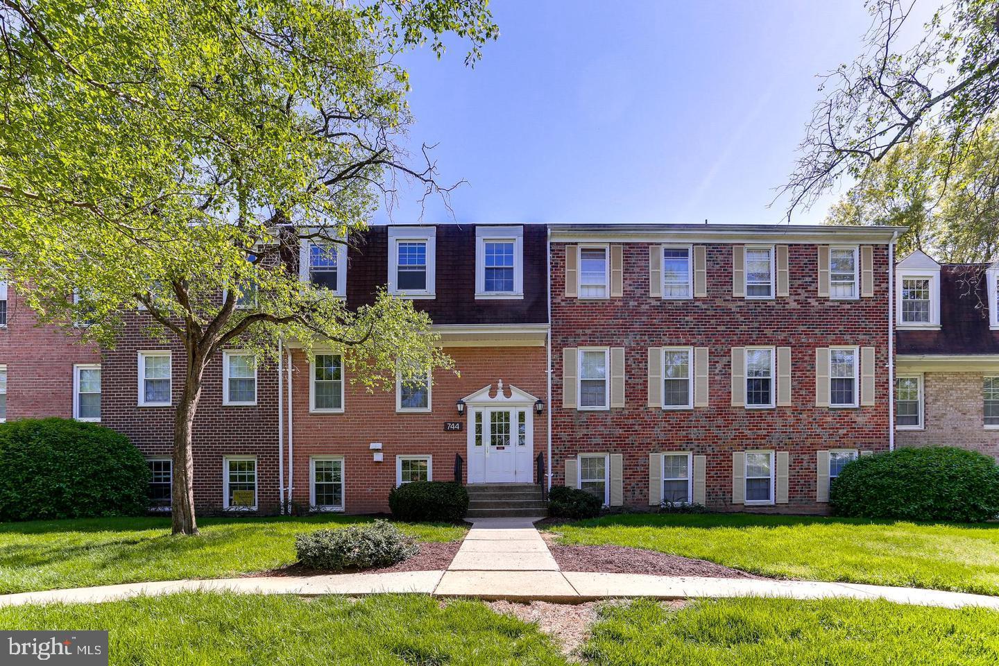 a view of a brick building next to a yard with big trees