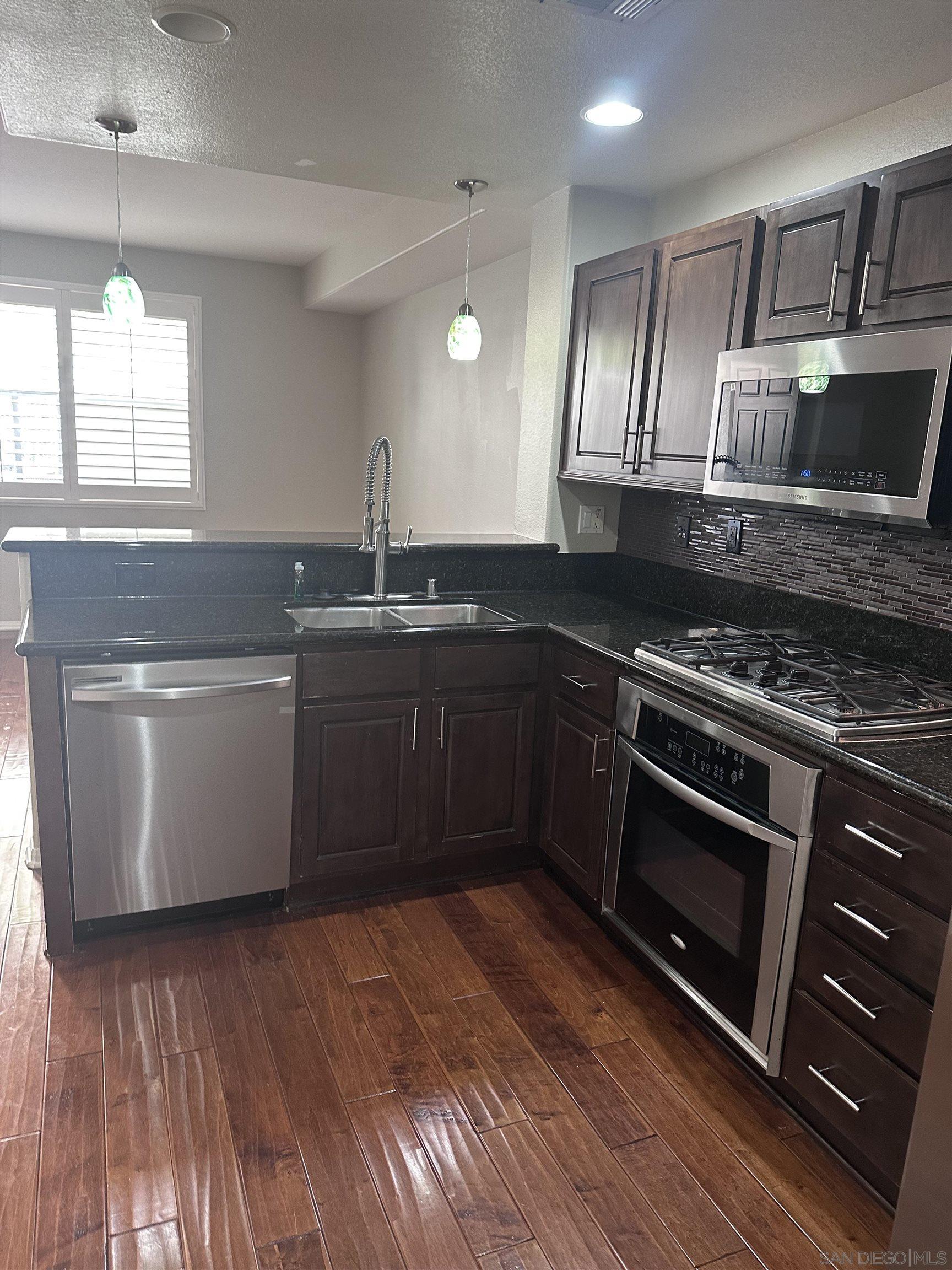 a kitchen with stainless steel appliances granite countertop a stove a sink and a microwave