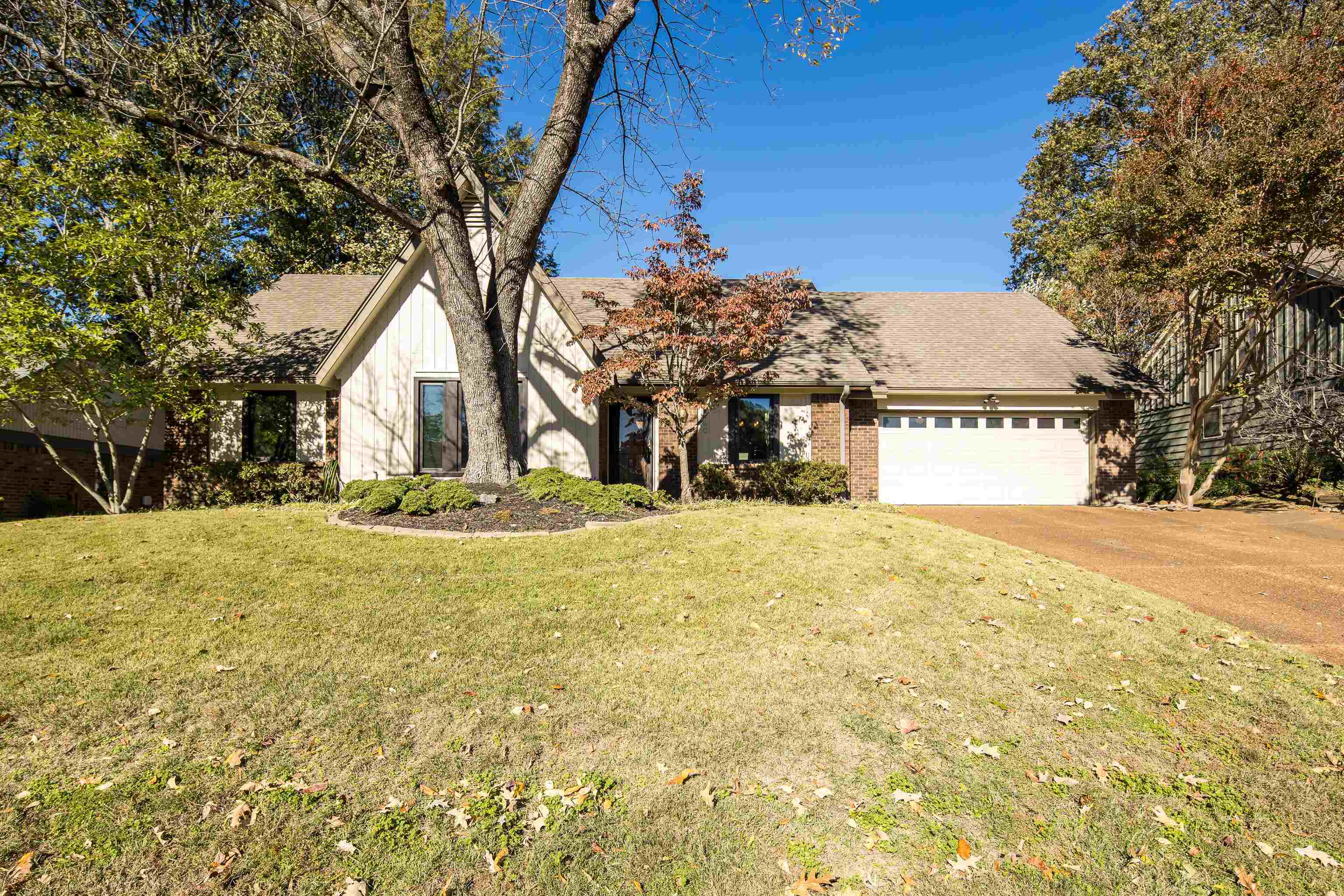 a view of yellow house with large trees