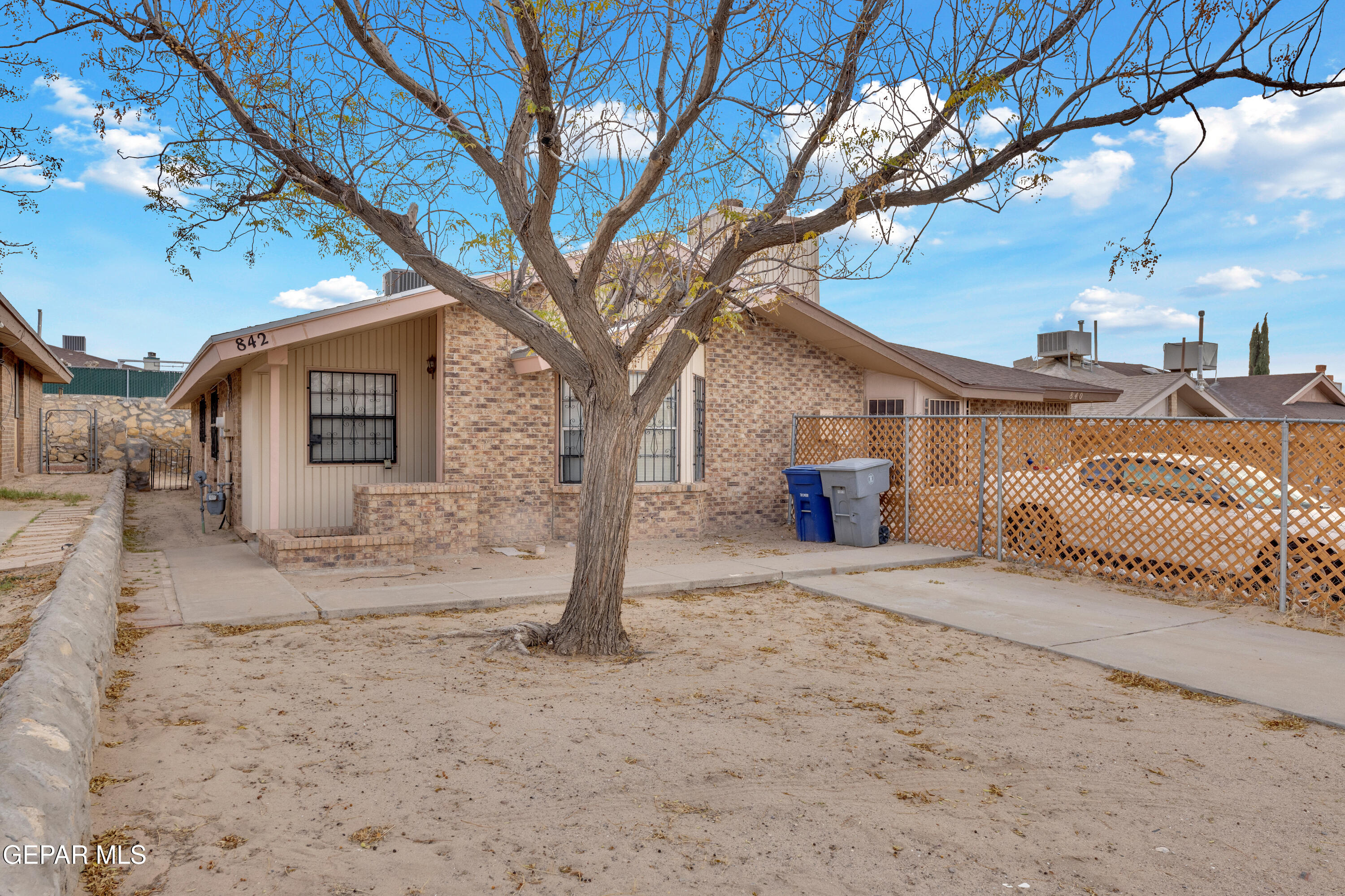 a front view of a house with a dirt yard and a large tree