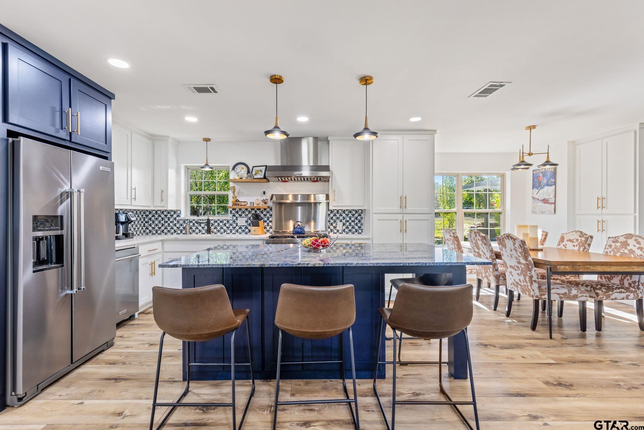 a kitchen with stainless steel appliances a dining table chairs stove and refrigerator