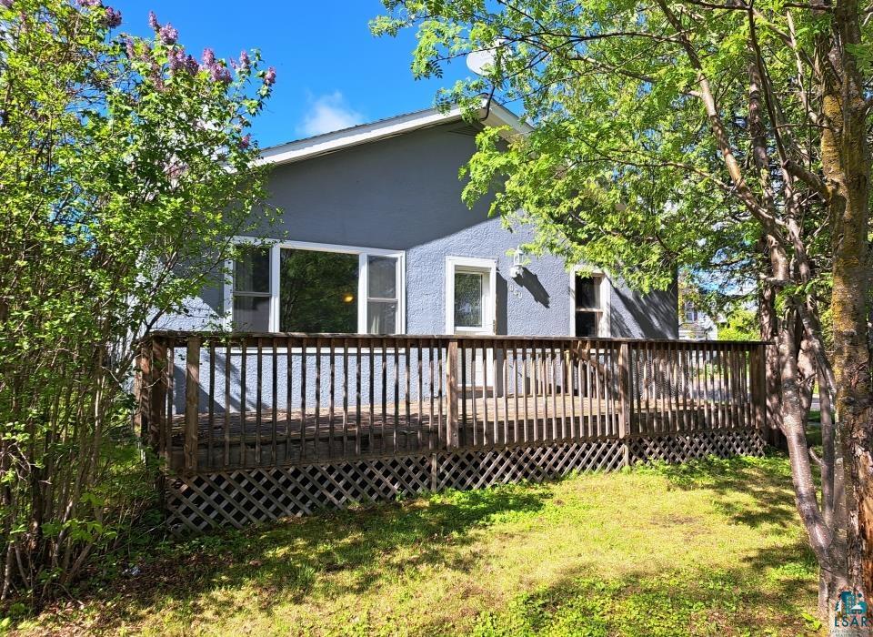 Back of property featuring a lawn and a deck