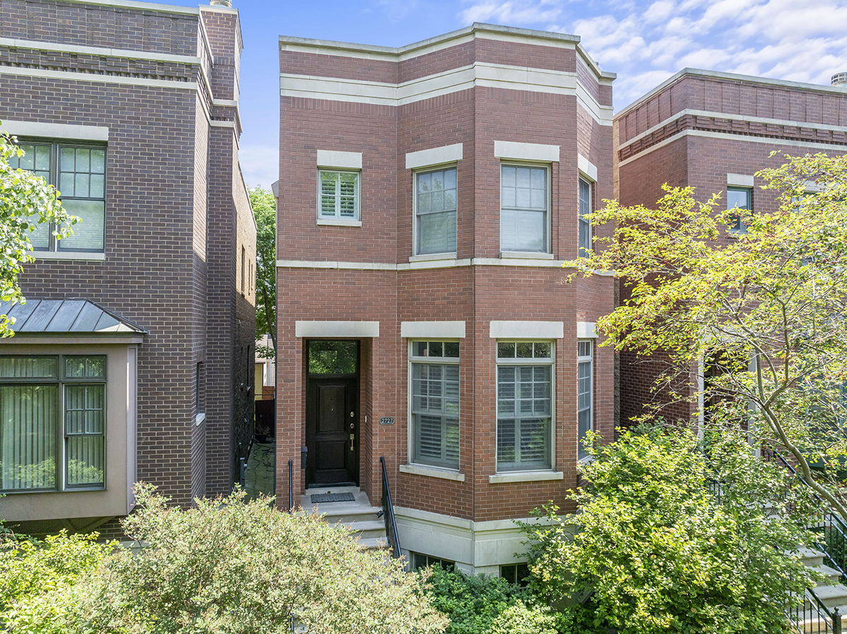 front view of a brick house with a large window and potted plants