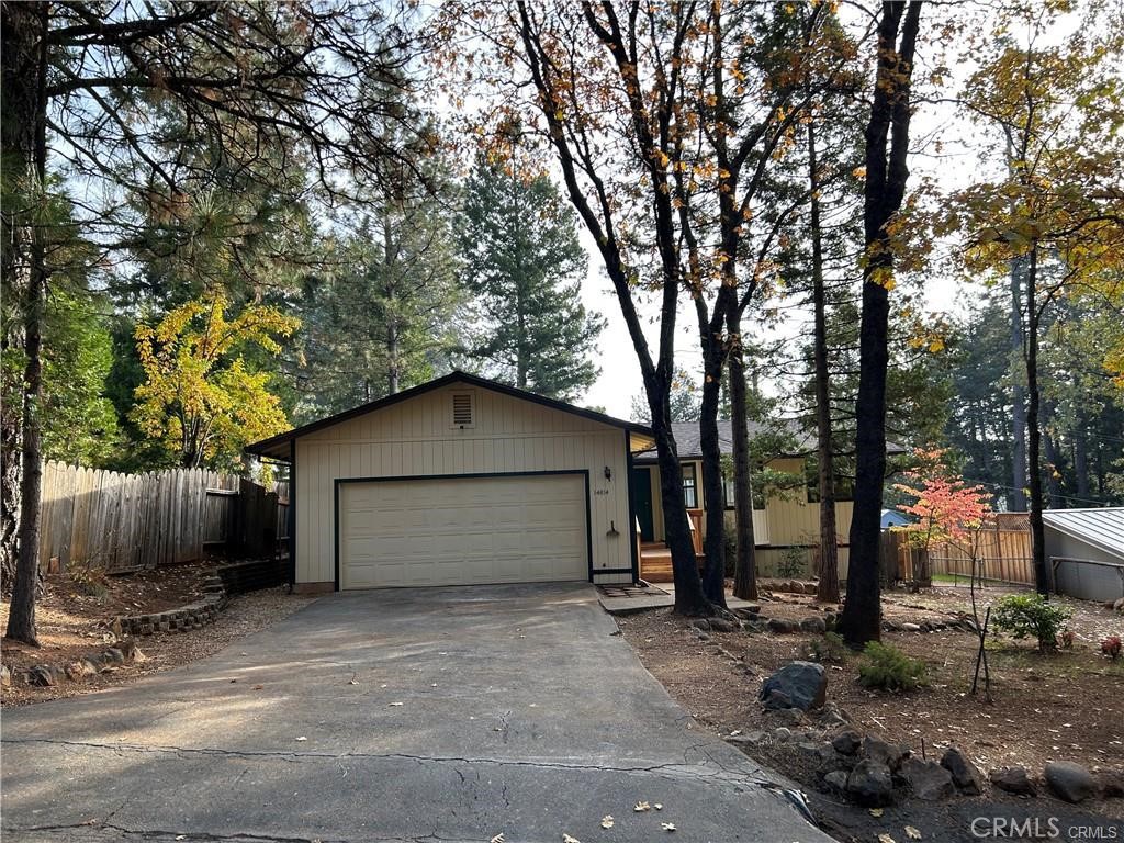 a view of a house with a garage and large tree