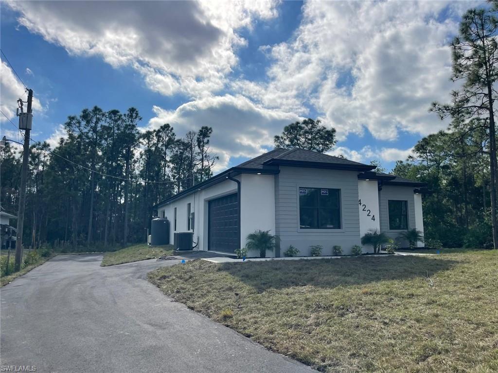 Ranch-style house with a garage, central air condition unit, and a front yard