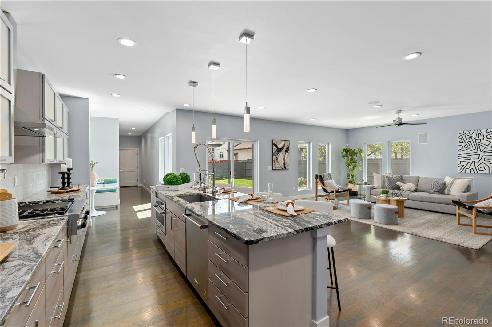 a living room with stainless steel appliances granite countertop a couch and a view of kitchen