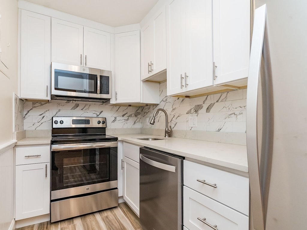 a kitchen with granite countertop cabinets stainless steel appliances and a wooden floor