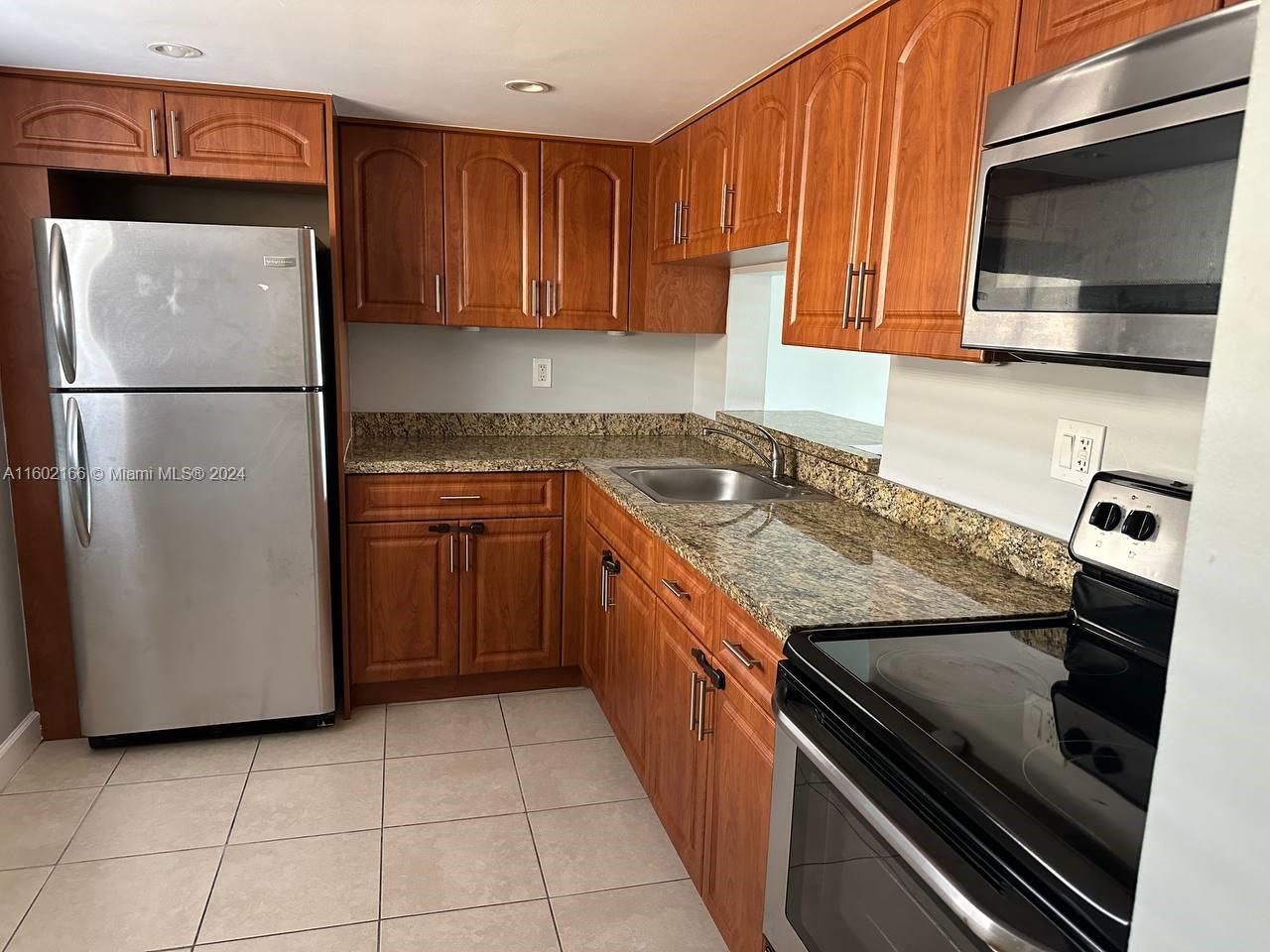 a kitchen with granite countertop a refrigerator and a stove top oven