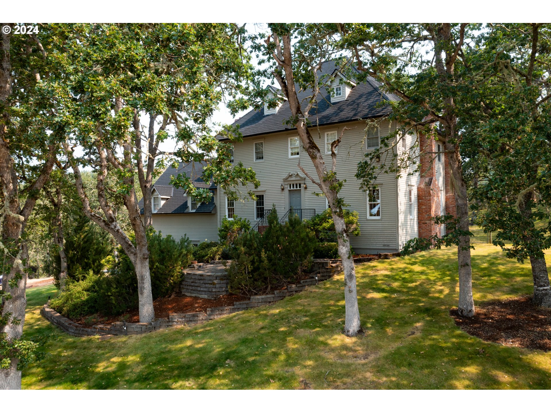 a backyard of a house with plants and large trees