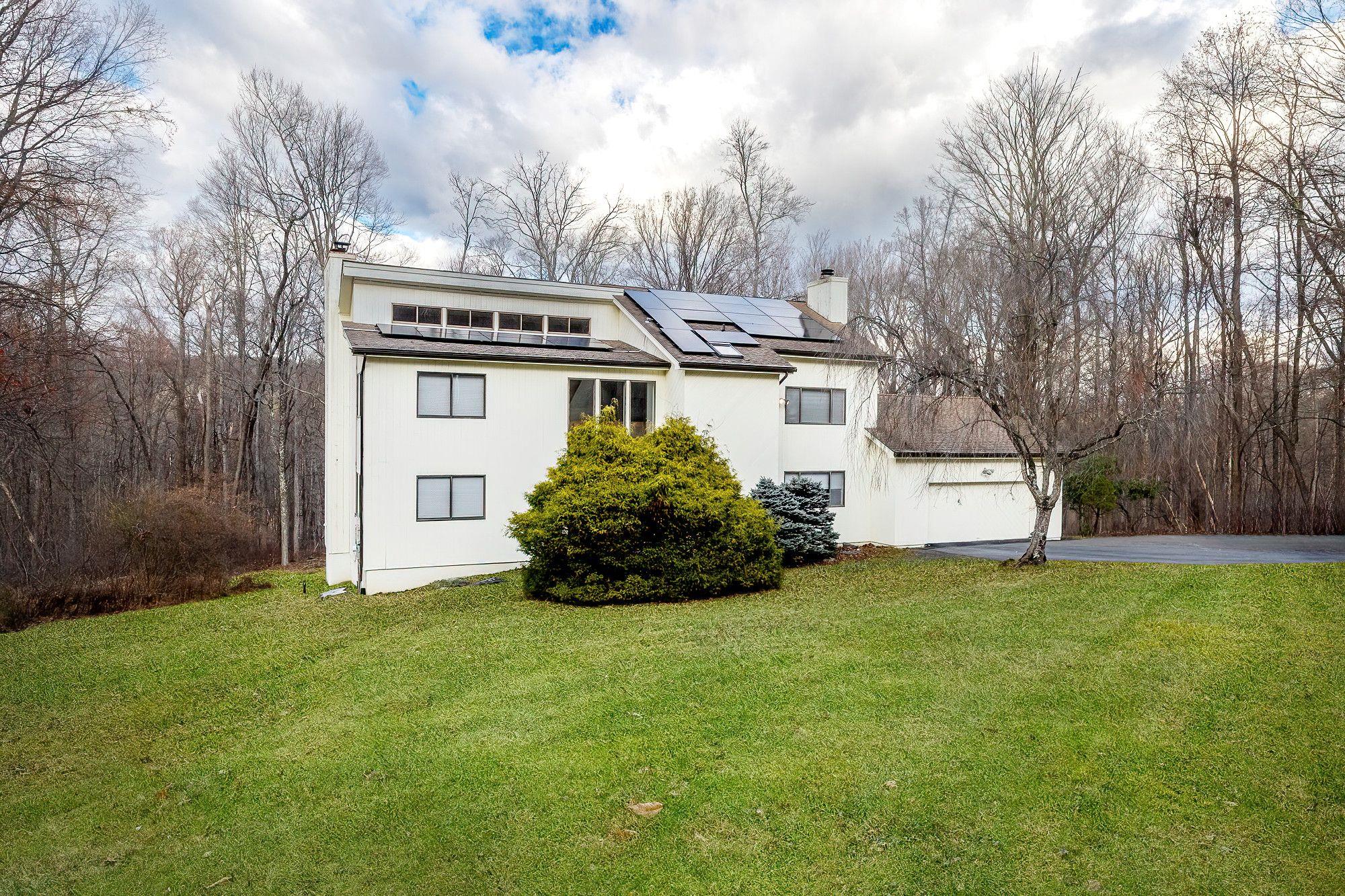 View of property exterior featuring a lawn, a garage, and solar panels