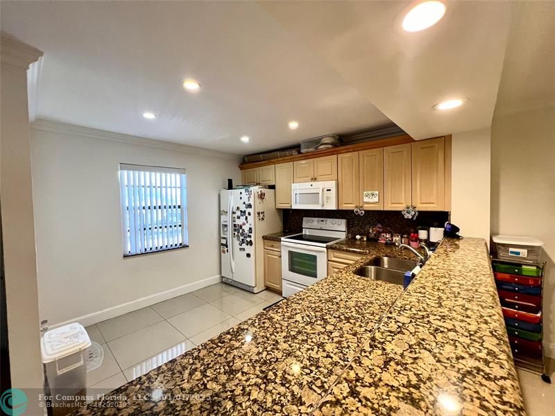 a kitchen with stainless steel appliances kitchen island granite countertop a refrigerator and cabinets